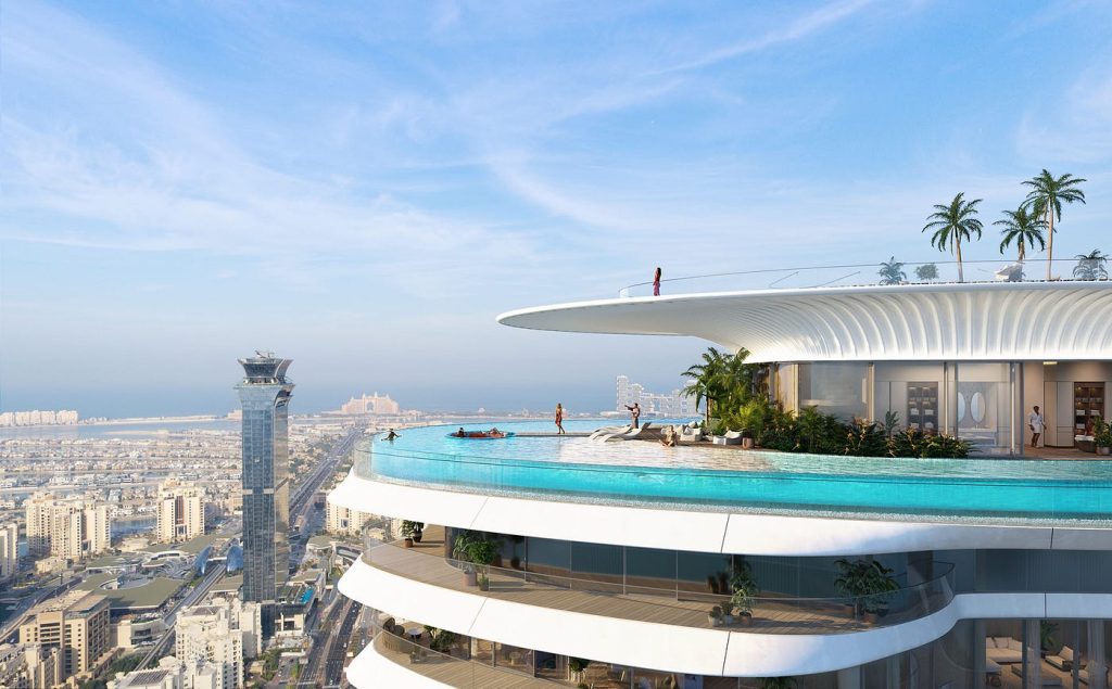 A futuristic high-rise building, Como Residences, boasts a rooftop infinity pool with panoramic city views. Palm trees and a few people enjoying the pool can be seen. The surrounding cityscape features modern skyscrapers and a distant view of the coastline with an island. | RealEstateMarket