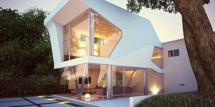 A modern two-story luxury real estate property with an asymmetrical, angular design featuring large glass windows. The ground floor has an open-plan living area visible through the glass walls. Surrounded by greenery, the house boasts a tree and a tiled patio in the foreground. | RealEstateMarket
