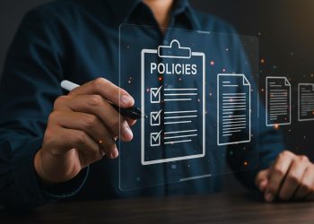 A person in a dark shirt using a digital pen interacts with a virtual screen displaying icons of documents, including a clipboard labeled “POLICIES” with checkmarks next to listed items. | RealEstateMarket