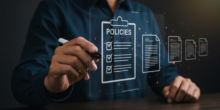 A person in a dark shirt using a digital pen interacts with a virtual screen displaying icons of documents, including a clipboard labeled “POLICIES” with checkmarks next to listed items. | RealEstateMarket