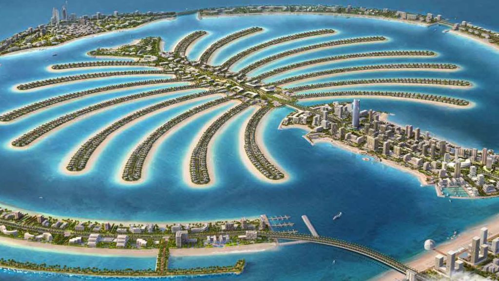 Aerial view of Palm Jumeirah in Dubai, an iconic artificial island shaped like a palm tree, with frond-shaped sections extending into turquoise water, lined with buildings and lush greenery. | RealEstateMarket